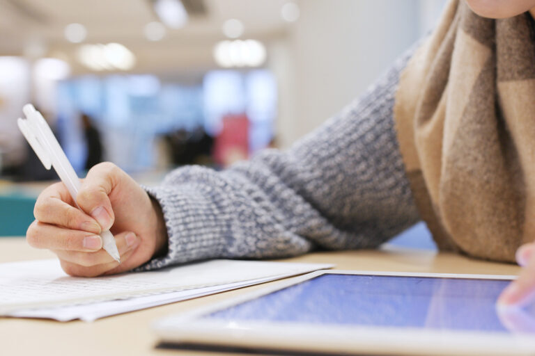 Ein Mädchen arbeitet parallel mit einem Tablet und Heft