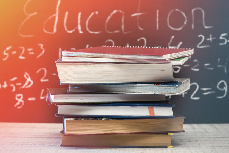Gestapelte Bücher auf einem Tisch vor einer Tafel